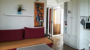 Quarto moderno com sofá, um quadro, uma planta em vaso e um guarda-roupa.