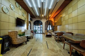 A modern lobby with a TV, seating area, and a large table.