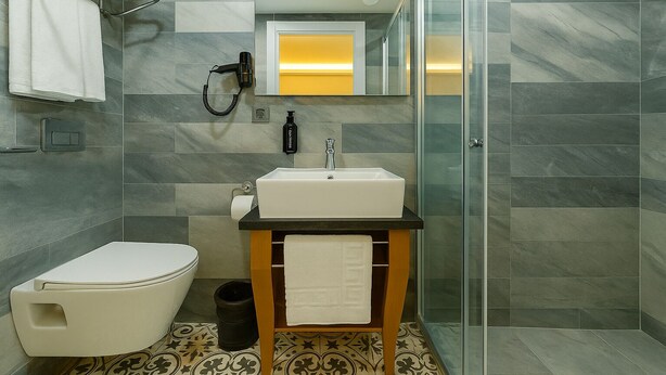 A modern bathroom with a white sink, toilet, and shower area. - FRT Airport Hotel (Arnavutköy)