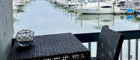 A covered outdoor area with a table and chairs, overlooking a marina with boats docked.