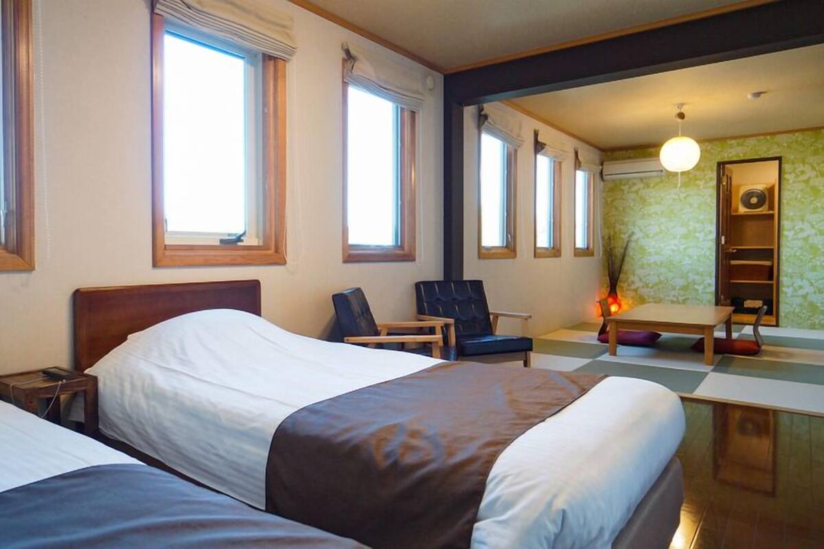 Ein Hotelzimmer mit zwei Betten, einem Schreibtisch, einem Stuhl und einem kleinen Tisch.