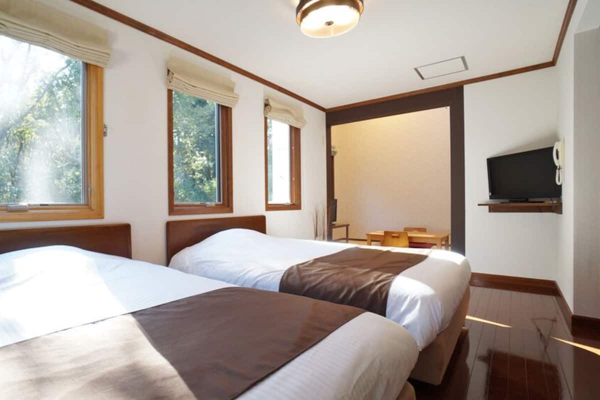 Ein Hotelzimmer mit zwei Betten, einem Fernseher und einem Fenster mit Vorhängen.
