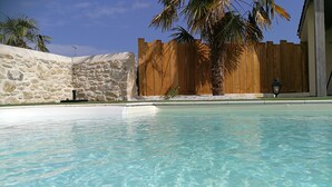 A clear swimming pool with a stone wall and wooden fence in the background. - ★★★ SPIRIT BOHÈME CHIC for an inspiring and breathable stay in Haute Gironde ★★★ (CARTELEGUE)