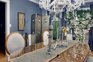 Un coin repas agrémenté d’un lustre, d’un sapin de Noël et d’une table dressée dans un style moderne.