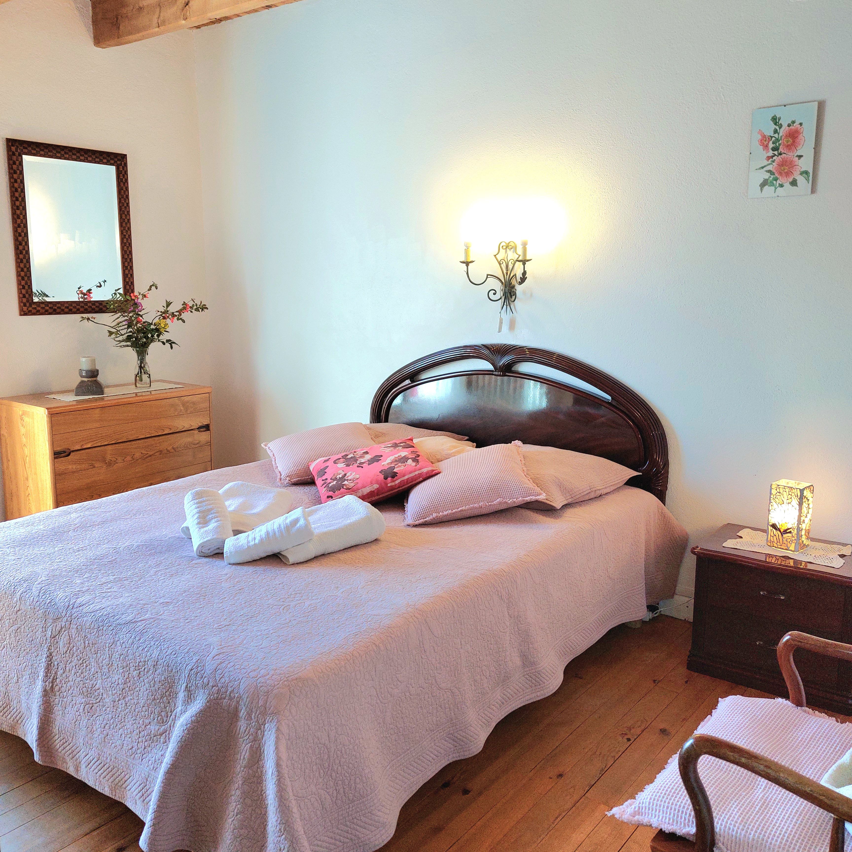 Une chambre à coucher avec une tête de lit en bois, une table de chevet avec une lampe et un lit avec des oreillers et des serviettes.