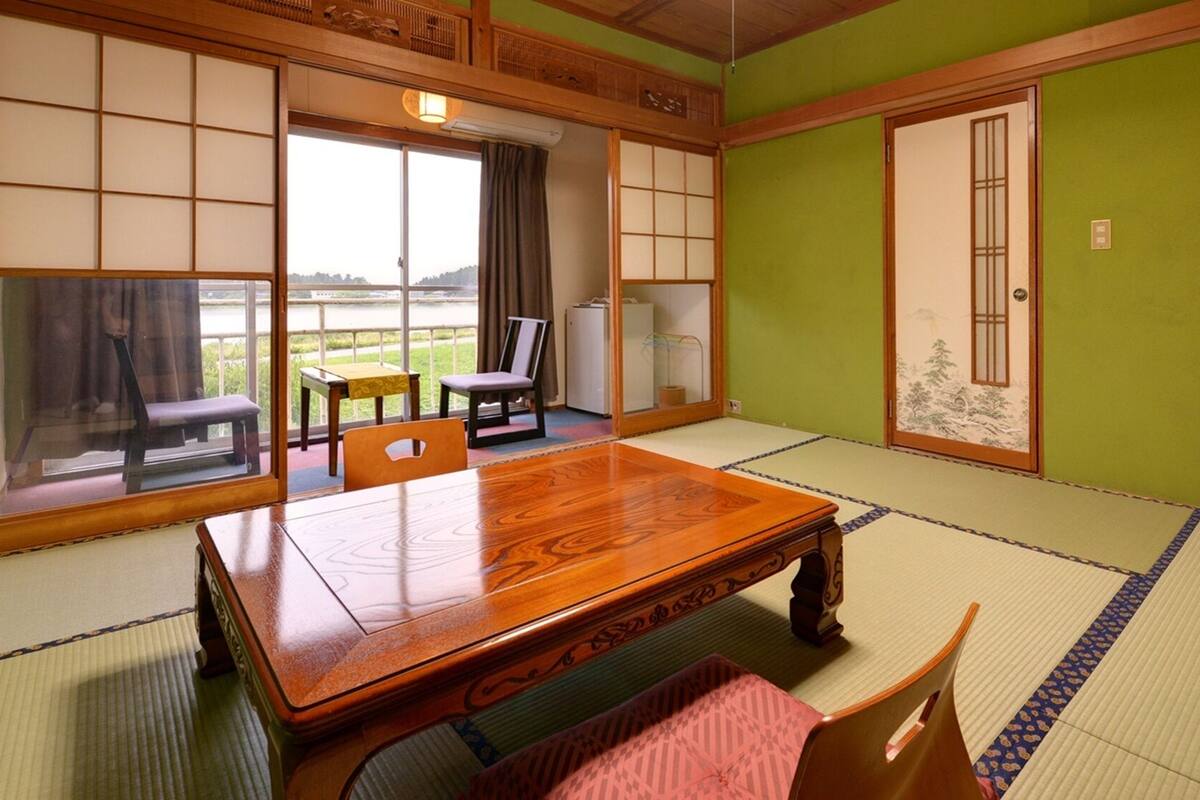 Una habitación tradicional japonesa con suelo de tatami, una mesa de madera y puertas correderas.