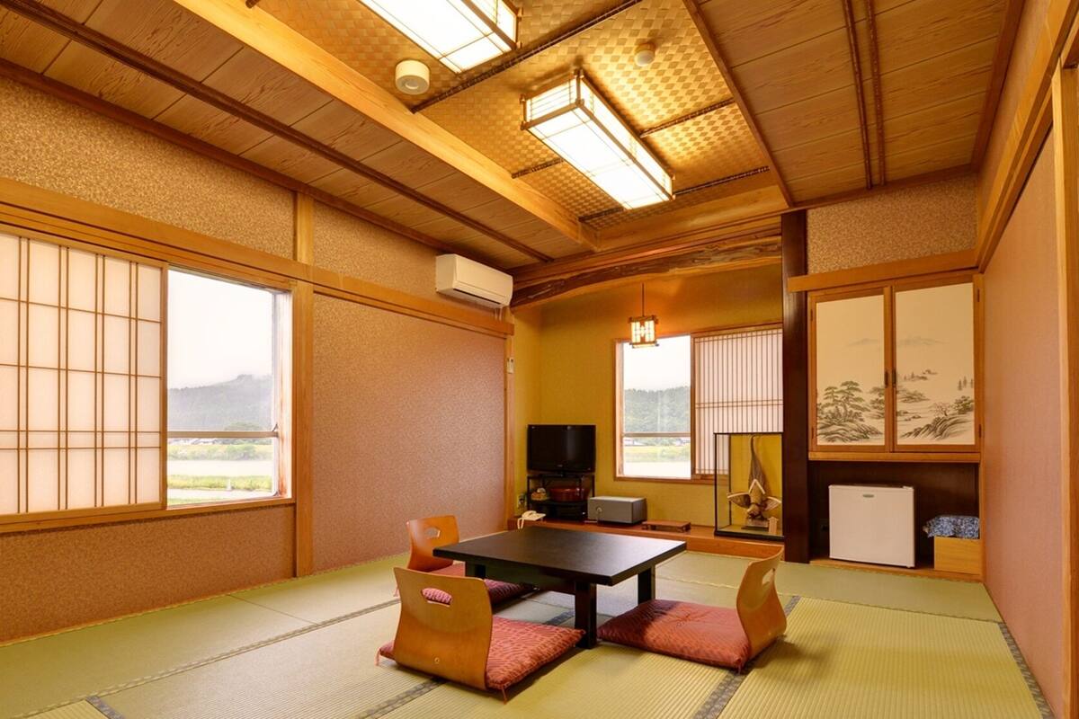 Una habitación japonesa tradicional con suelo de tatami, una mesa baja y puertas correderas.