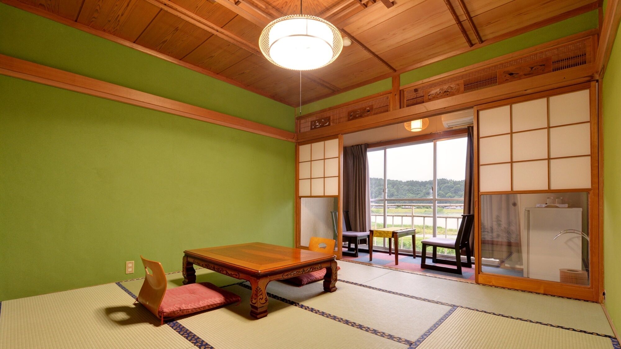 Ein Raum mit Tatami-Böden, einem Holztisch, Stühlen und Blick durch einen Shoji-Bildschirm.