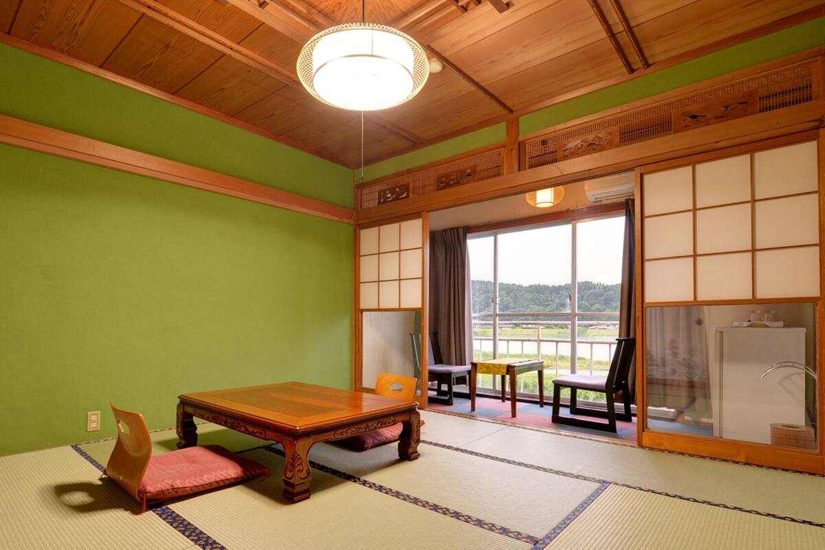 Una habitación de tatami con una mesa de madera, sillas y vistas a través de un biombó shoji.