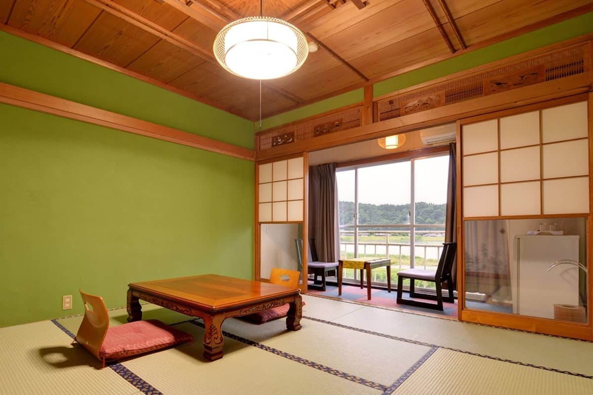 A tatami room with a wooden table, chairs, and a view through a shoji screen.