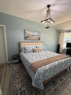 Een slaapkamer met een bed, een schilderij, een kroonluchter en een raam.