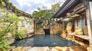 A traditional Japanese garden with a koi pond, stone lanterns, and a wooden structure. - Gyokusenkan (Ebino)