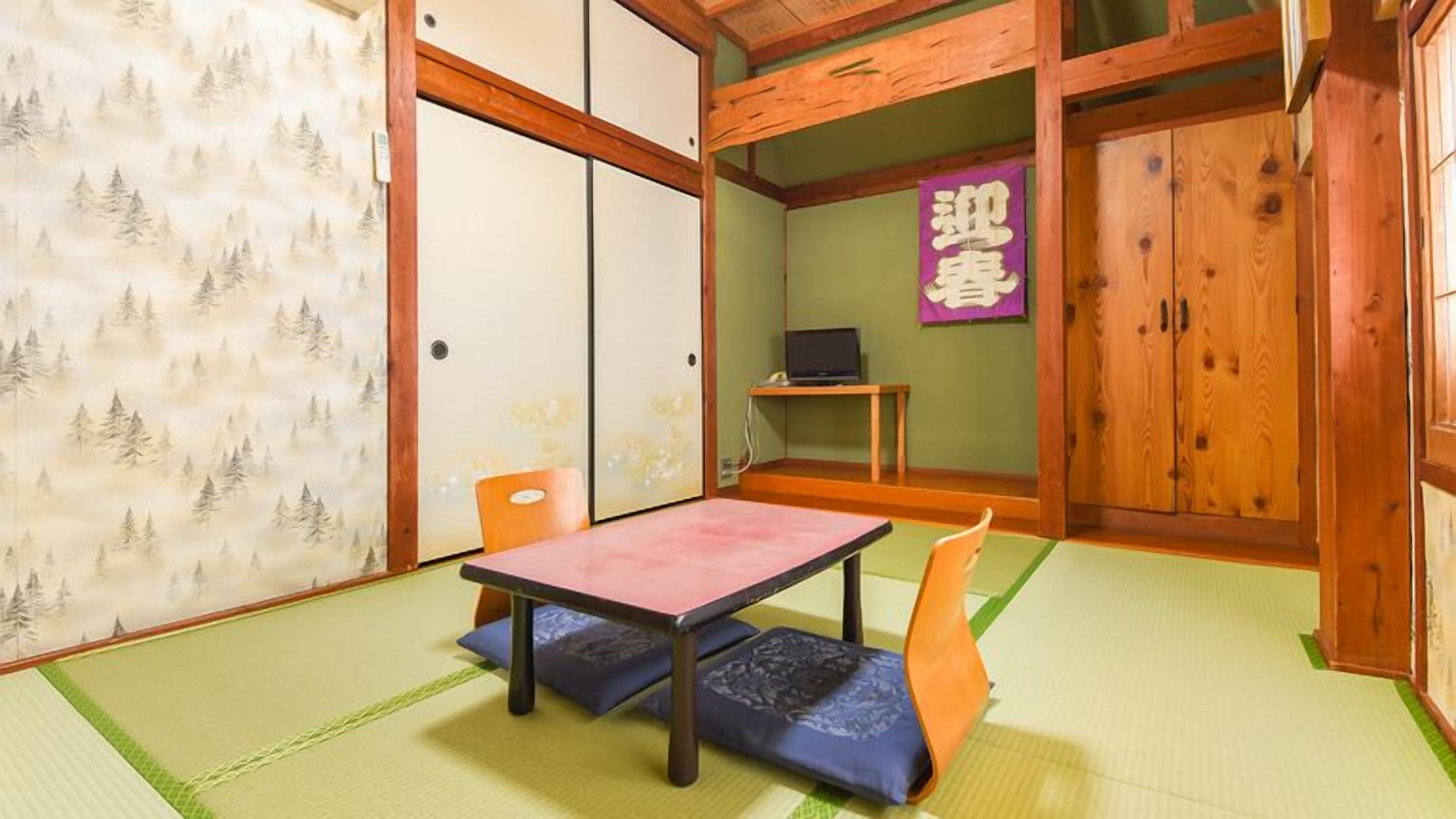 A traditional Japanese room with tatami flooring, a low table, a chair, and a television on a shelf.