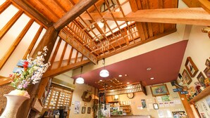 A traditional inn with exposed wooden beams, a wooden staircase, and a variety of framed pictures on the walls. - Gyokusenkan (Ebino)