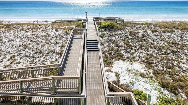 A wooden boardwalk leading to a beach with a clear view of the ocean.
