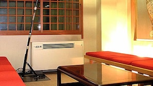 Una habitación con ventana, un paraguas rojo, una mesa y un banco.