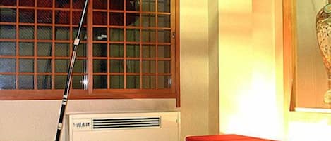 A room with a window, a red umbrella, a table, and a bench.