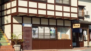 Un edificio japonés tradicional con techo a dos aguas, vigas de madera y un pequeño balcón.