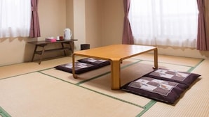 Una habitación con suelo de esteras de tatami, una mesa baja, un estante con objetos y una ventana con cortinas.
