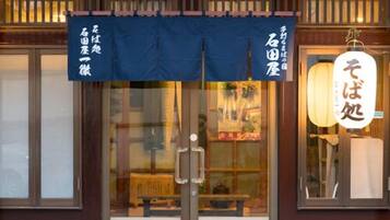 Un restaurante japonés tradicional con puerta de vidrio corredera, un toldo oscuro y un farol colgante.