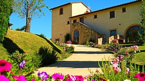 A building with a stone facade, a stone staircase leading to the entrance, and a garden with flowers. - LE BUCHE ESTATE  VILLA RENTAL  (Sarteano)