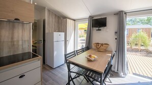 Una cocina compacta con estufa integrada, un refrigerador y un comedor con mesa y sillas.