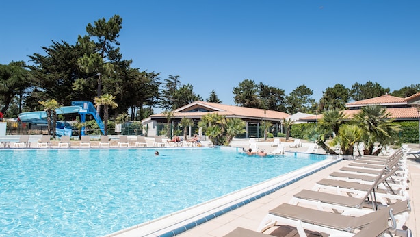 Una piscina con sillas de descanso y un tobogán de agua.