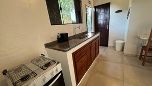 A kitchen with a gas stove, a microwave, and a sink. - Suíte em Geribá, Próximo a Praia (Armação do Búzios)