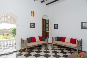 Una habitación con dos sofás de madera con cojines, piso a cuadros y cuadros enmarcados en las paredes.