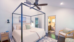 A bedroom with a four-poster bed, a ceiling fan, a nightstand, a chair, and a rug.