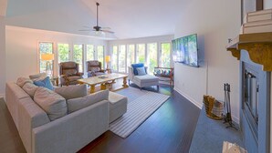 A spacious living room with a sofa, armchairs, a coffee table, and a fireplace.