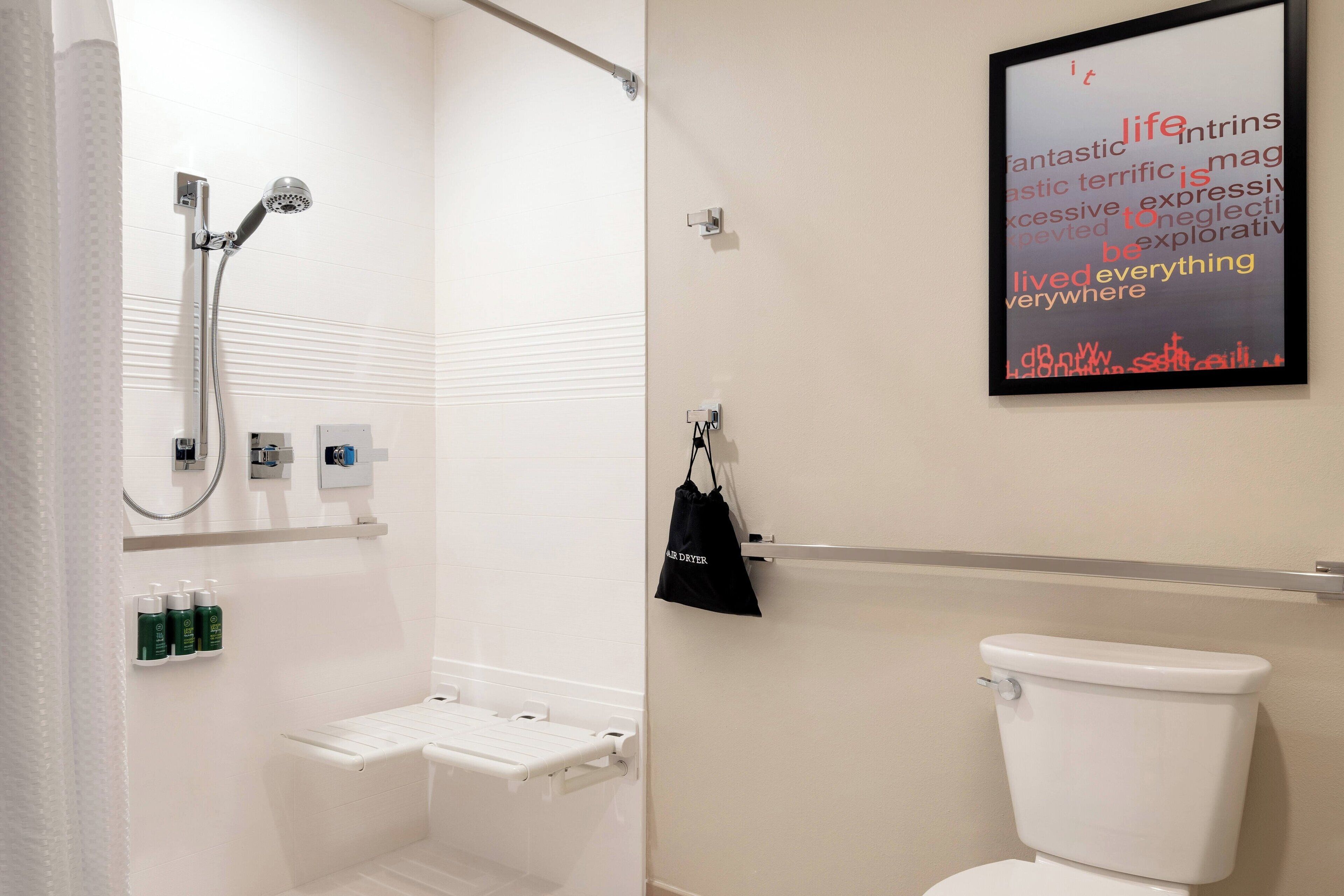 A bathroom with a shower, toilet, and a wall-mounted towel rack.