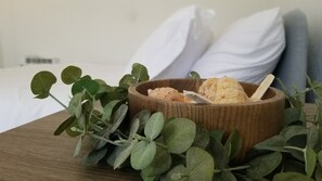 A wooden bowl with seashells and a wooden stick on a wooden table, surrounded by green leaves. - Hotel Motel Lauderdale Inn (Fort Lauderdale)