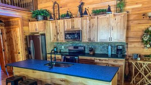 A spacious kitchen with wooden cabinets, a large island with bar stools, a microwave, oven, and a coffee maker.