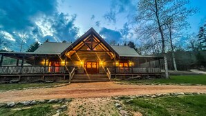 A lodge with a prominent triangular roof, a porch with railings, and a well-lit entrance.