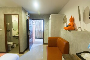 A modern interior with a hallway leading to a bathroom, a seating area with a sofa, and a decorative Buddha statue. - Baan Kamala Fantasea Hotel (Kamala)