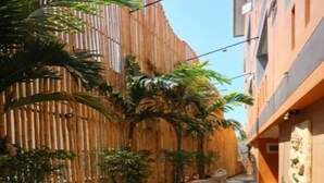 A narrow alleyway with a bamboo wall on one side and a building with a stone facade on the other. - Baan Kamala Fantasea Hotel (Kamala)
