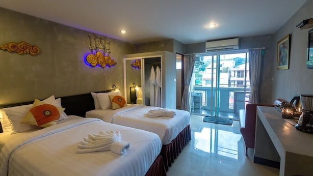 A hotel room with two beds, a desk, and a view of the outside. - Baan Kamala Fantasea Hotel (Kamala)
