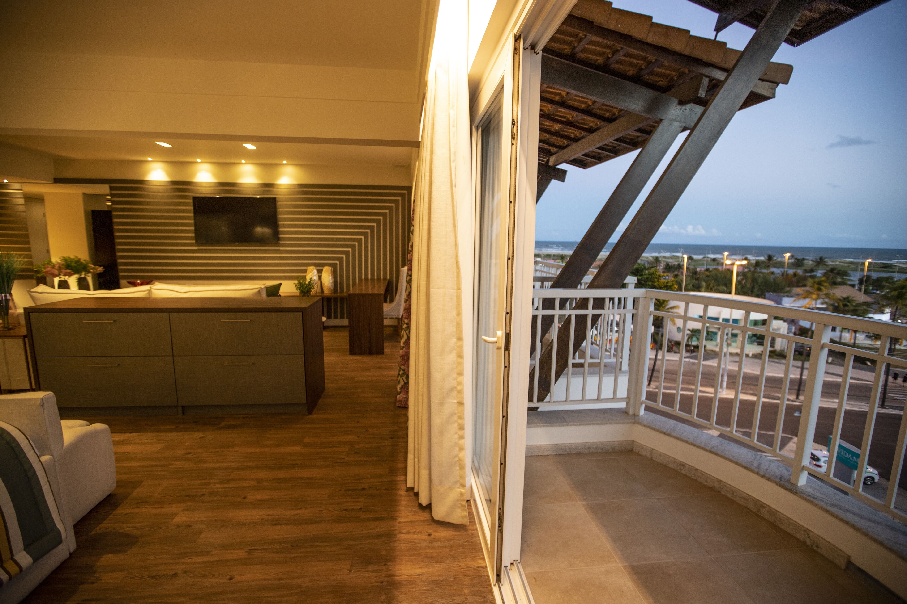 A modern interior with a kitchen, dining area, and a balcony with a view of the cityscape.