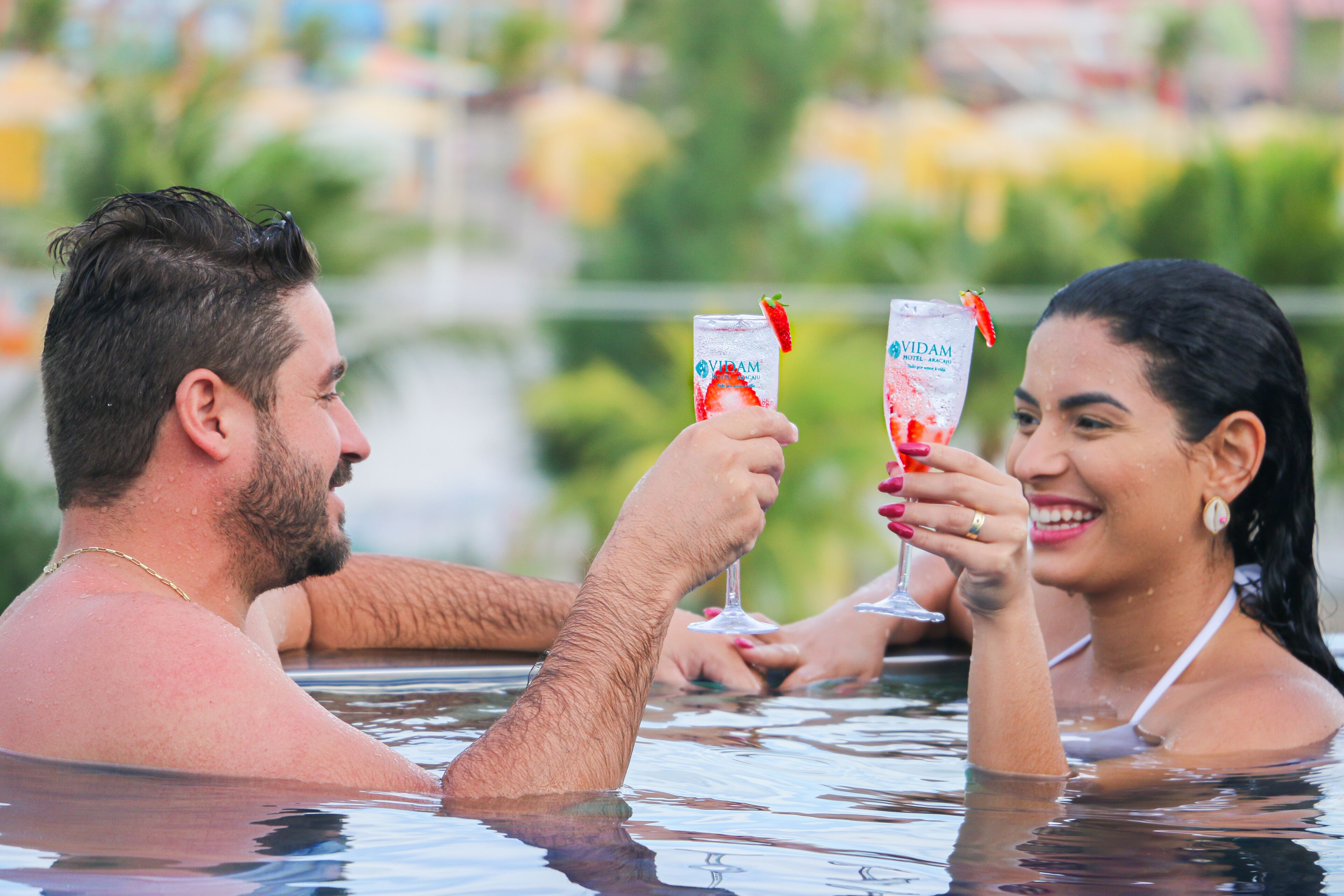 Two people in a hot tub with a clear view of a body of water and greenery in the background.