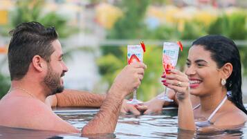 Two people in a hot tub with a clear view of a body of water and greenery in the background.