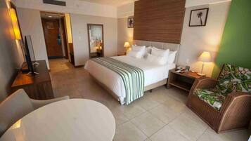 A hotel room with a bed, bedside table, lamp, chair, and a round table.