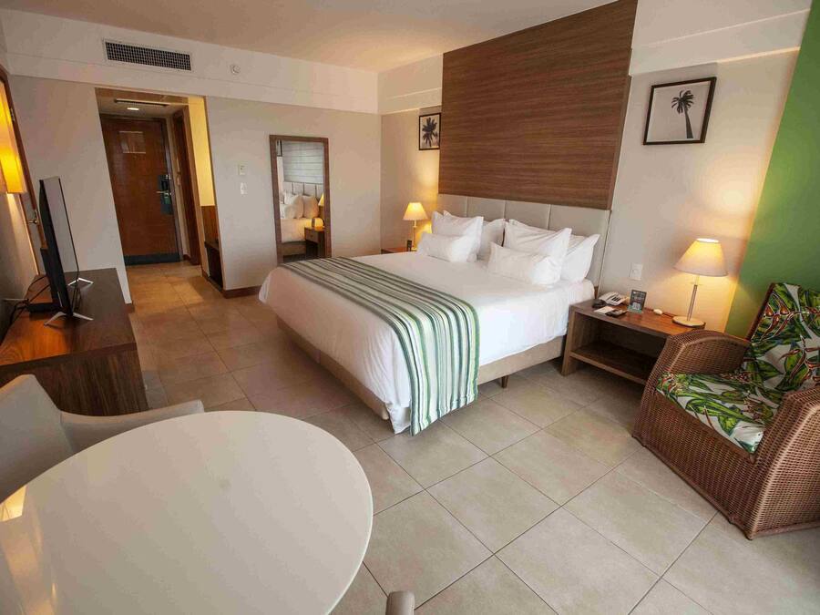 A hotel room with a bed, bedside table, lamp, chair, and a round table.