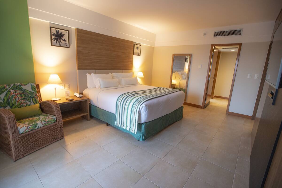A hotel room with a bed, a nightstand, a chair, and a lamp.