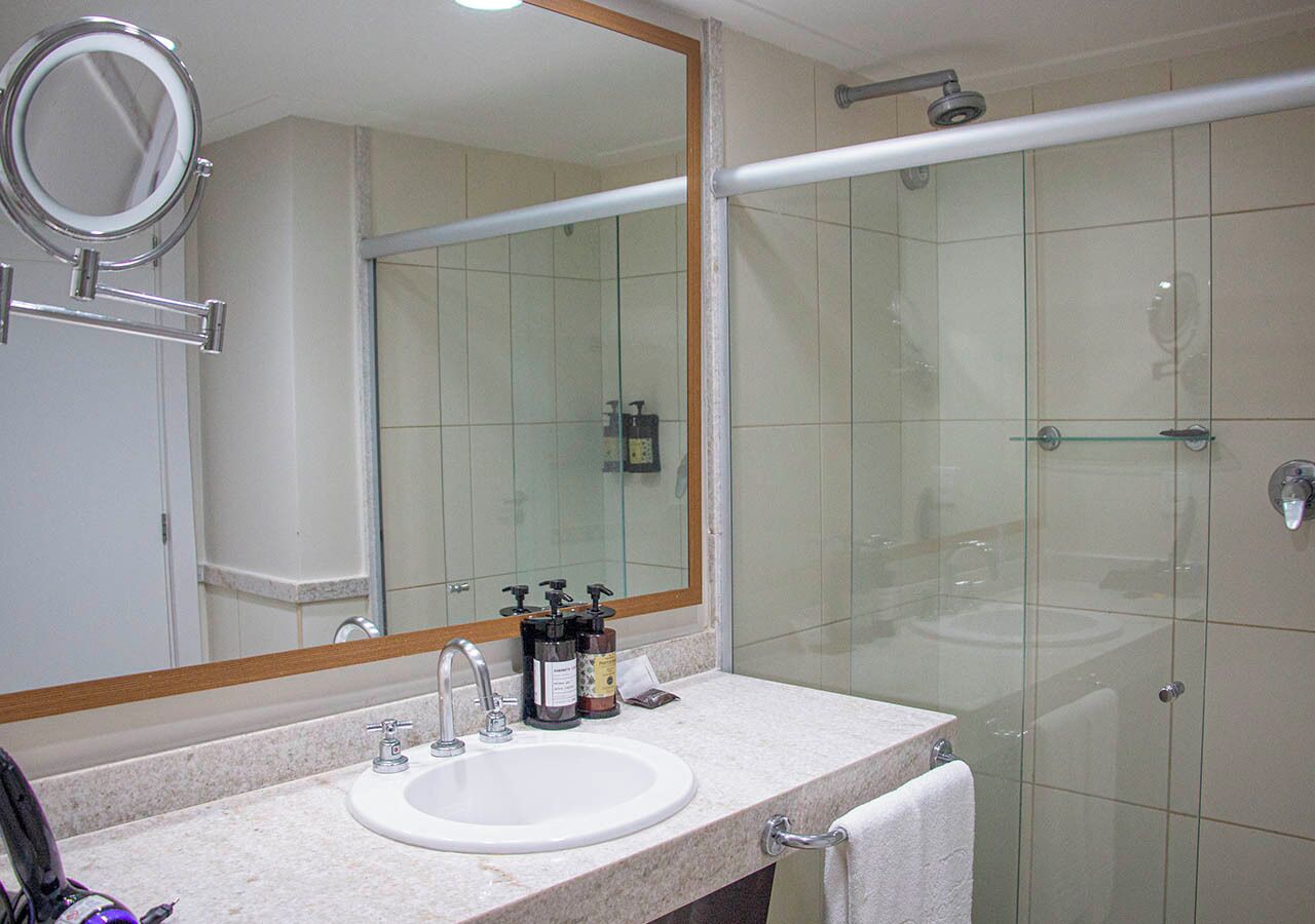 Un baño con lavamanos, espejo y cabina de ducha de vidrio.