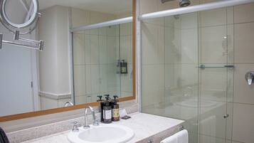 Un baño con lavamanos, espejo y cabina de ducha de vidrio.