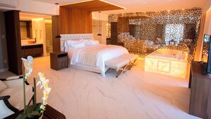 Un dormitorio moderno con una cama grande, una mesita de noche pequeña, un banco, un muro decorativo y una bañera.