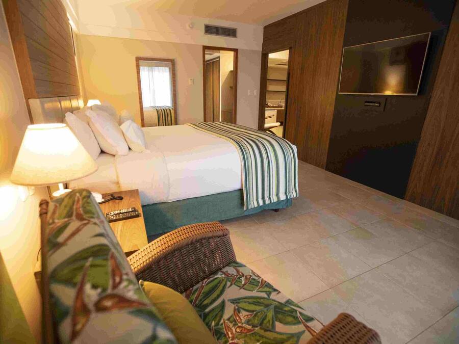A hotel room with a bed, a TV, a sofa, and a bathroom visible through an open door.
