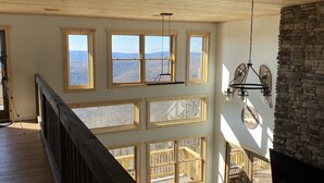 A spacious room with multiple large windows offering views of the outdoors, a wooden ceiling, and a stone wall. - Great Family Vacay! Luxury 6 BR 300 ft to Cupp Run Hot Tub In&Outdoor Fireplace (Snowshoe)