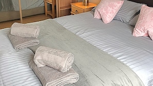 Et hotelværelse med to senge, et træskab, et natbord med lampe og et spejl.
